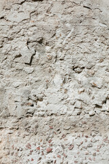 An old weathered wall. Plastered stone surface with small rocks. Grunge texture background.