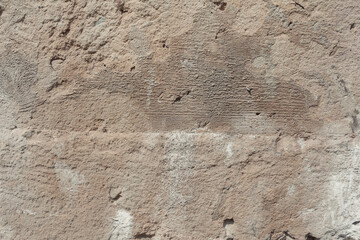 A stone plastered surface with damages. Beige background texture. Weathered old wall with detailed texture.