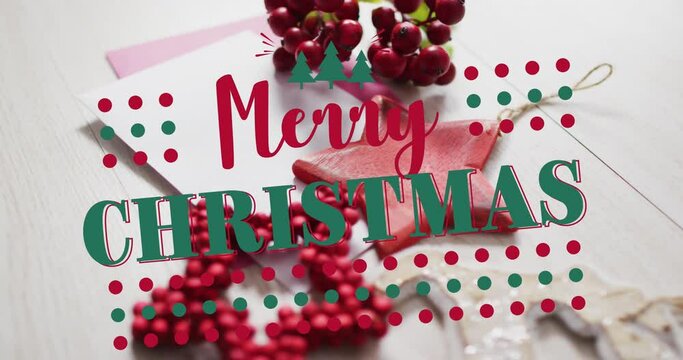 Animation of merry christmas text over christmas decorations and envelopes