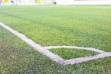 Close up shot of white line of chalk for corner symbol on lawn or grass in soccer field under...