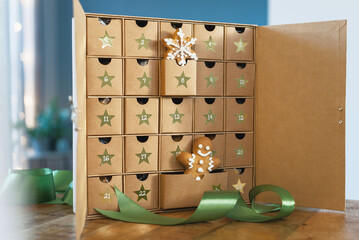 Christmas advent calendar of gingerbread and sweets in a craft box is on the table.