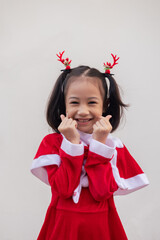 Portrait shot of adorable asian kid girl with red sweater for Christmas costume on white background shows concept of happiness celebration. It is the emotional face expression of enjoyment.