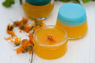 Making homemade organic calendula ointment, warm cream in small glasses.  Medicinal cream from dryed marigold flowers good for skin.. - obrazy, fototapety, plakaty