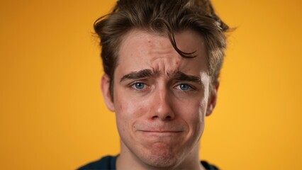 Closeup portrait of sad, unhappy, angry, upset, frustrated, young man 20s isolated on yellow color background in studio. Sincere emotions lifestyle concept