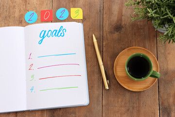 Business concept of top view 2023 goals list with notebook, cup of coffee over wooden desk