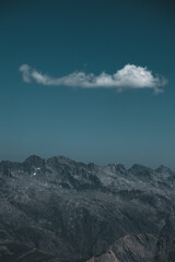 Fototapeta na wymiar a single cloud is hanging above the mountains in the alps, France