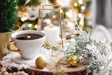 Lifestyle. A cup of tea, a Christmas tree, candles and golden balls on a wooden table against a beautiful bokeh background during the Christmas holidays. Still-life. The concept of home warmth,comfort