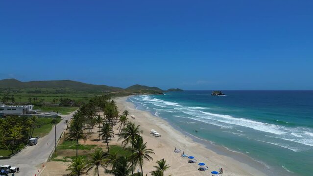 Aerial view of the El Agua tropical beach on the Margarita island. Tall palm trees, turquoise water and big waves. Vacation in beautiful Venezuela