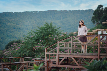 Asian female tourists looking at nature with the morning atmosphere on the mountain in Thailand She is happy with the natural mountain view. concept of women traveling in Thailand
