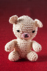 Petit ourson brodé en fil blanc sur une nappe rouge