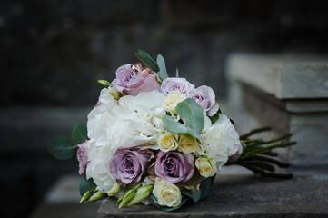A pair of gold wedding rings on a bride's bouquet with colorful flowers