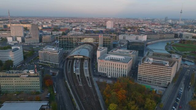 Complex of modern office buildings around Main train station near river. Aerial view of Berlin Hauptbahnhof and metropolis at dusk in background. Berlin, Germany