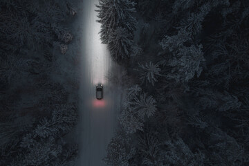 A passenger car moves along a forest winter road at night. Winter, Christmas theme