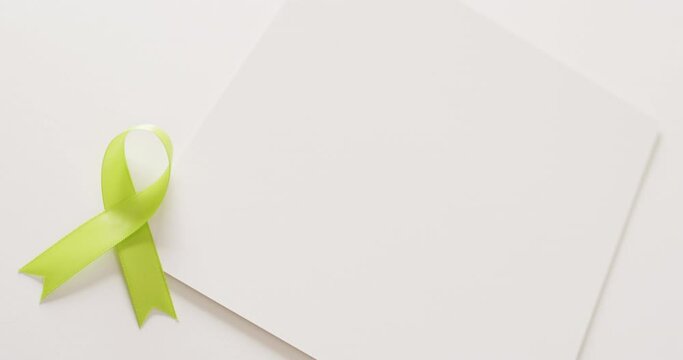 Video of pale green std awareness ribbon and white card with copy space, on white background