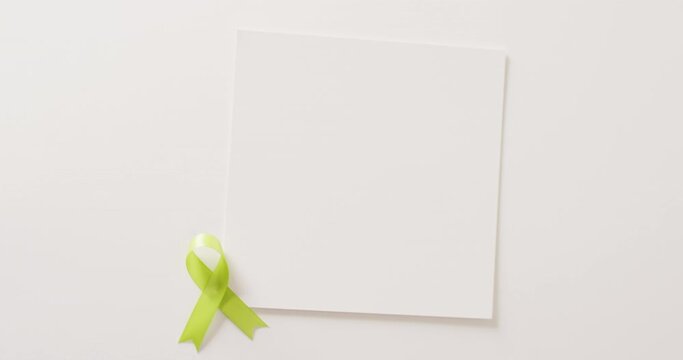 Video of pale green std awareness ribbon and white card with copy space, on white background