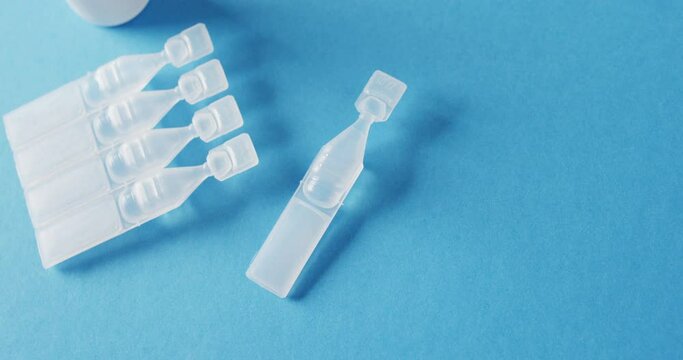 Video of saline caplets and dropper bottle on blue background with copy space