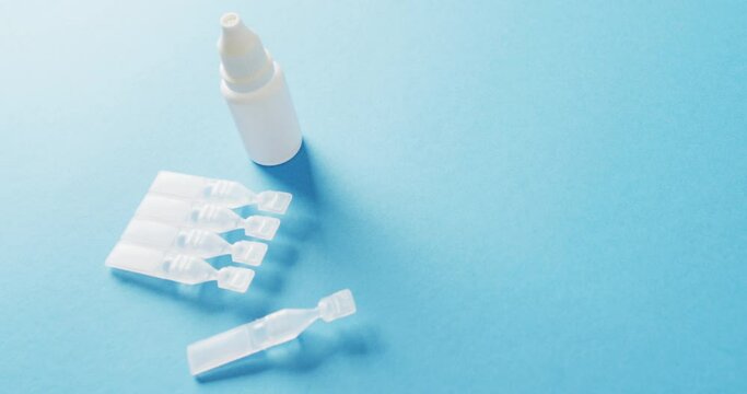 Video of saline caplets and dropper bottle on blue background with copy space
