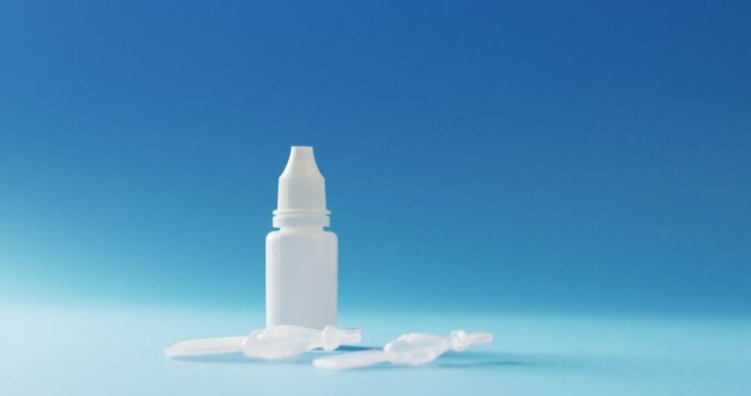 Video of saline caplets and dropper bottle on blue background with copy space