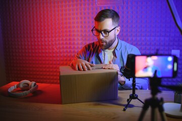 Obraz na płótnie Canvas vlogger using smartphone to film podcast in studio. blogger with mobile phone, microphone and headphones filming video for social media broadcasting career.