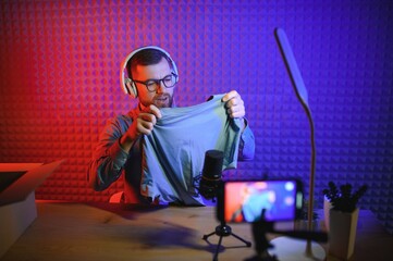 Fashion blogger recording video content, unboxing new sweater at home. Millennial influencer...