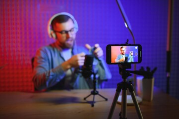 Fashion blogger recording video content, unboxing new sweater at home. Millennial influencer unpacking box with new clothes in front of professional camera, live streaming for social media.