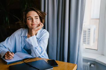 Beautiful woman smiling while writing down notes in office
