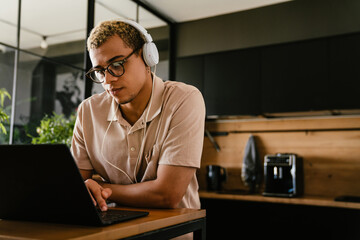 Young african businessman working on laptop computer while sitting at coffee area in office