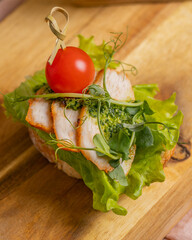 Bruschetta with chicken, tomato and pesto closeup on wood
