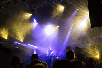 Dj playing techno music on the concert stage at summer night