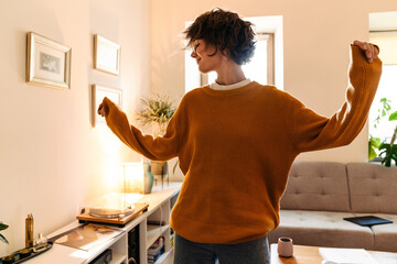 Brunette young woman in eyeglasses dancing while listening music