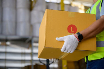 Close-up shot of male worker lifting cardboard boxes inside a retail warehouse with logistical...