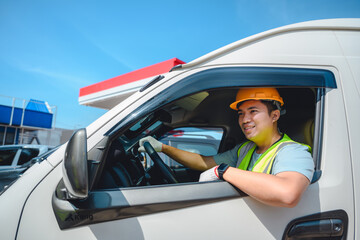 A young Asian man is a professional parcel delivery driver. Sitting in a cargo van with boxes in the car work for delivery driver Parcel delivery service to people in business areas