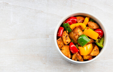 Food healthy stir fried chicken add sweet peppers in bowl on wood table.