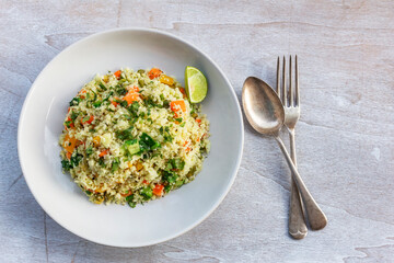 Healthy food cauliflower fried rice has vegetable in white dish on wood table.
