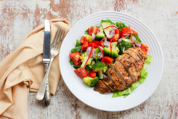 Healthy food grilled chicken vegetable salad in plate on white wood background.
