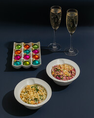 Two traditional Russian and Ukranian  salads: Olivier and herring under a fur coat with champagne and new year decoration on dark blue background 