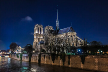 Illuminated Notre Dame de Paris Cathedral with the spire, before the fire at night, world most famous Gothic Roman Catholic cathedral in Paris, France