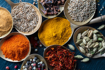 Fototapeta na wymiar Set of spices in brass spoons, closeup, top view. Various peppers, cardamom, carnation, turmeric, paprika and saffron for cooking