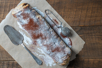Traditional freshly baked whole apple strudel on wooden table, closeup. Fresh homemade pastries with fruit or berry filling