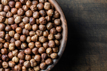 Dry hazelnuts in a ceramic plate on a wooden background. Heap of peeled hazelnuts kernels, top view, copy space for text