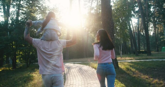 Asian family runs on paved path exploring morning park