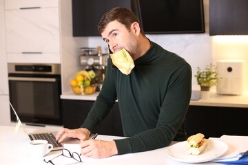 Busy man eating a sandwich while on conference call 