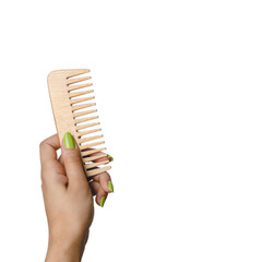 Woman hand holding bamboo hair comb in isolated white background. Zero waste and sustainability