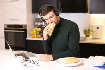 Busy man eating a sandwich while on conference call 