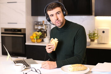 Busy man eating a sandwich while on conference call 