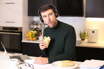 Busy man eating a sandwich while on conference call 
