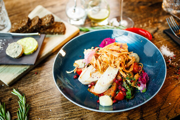 Warm salad with chicken. Almond potato, mini romaine lettuce, carrot, cherry tomato, pesto, black root chips, caramelized walnut, beet balsamic. Food closeup served for lunch in modern restaurant