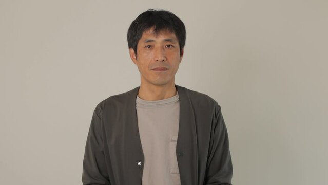 Middle aged Japanese man opens his eyes and stares the camera. Emotionless, Still, Protest. White background.