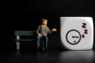 miniature figurine of an old man sitting on a bench showing an icon 