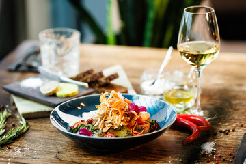 Warm salad with chicken. Almond potato, mini romaine lettuce, carrot, cherry tomato, pesto, black root chips, caramelized walnut, beet balsamic. Food closeup served for lunch in modern restaurant
